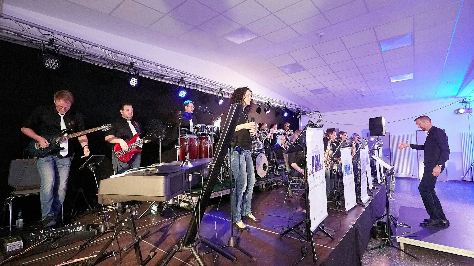 Die Musiker stehen auf der Bühne, vor ihren dirigiert Peter Blum.