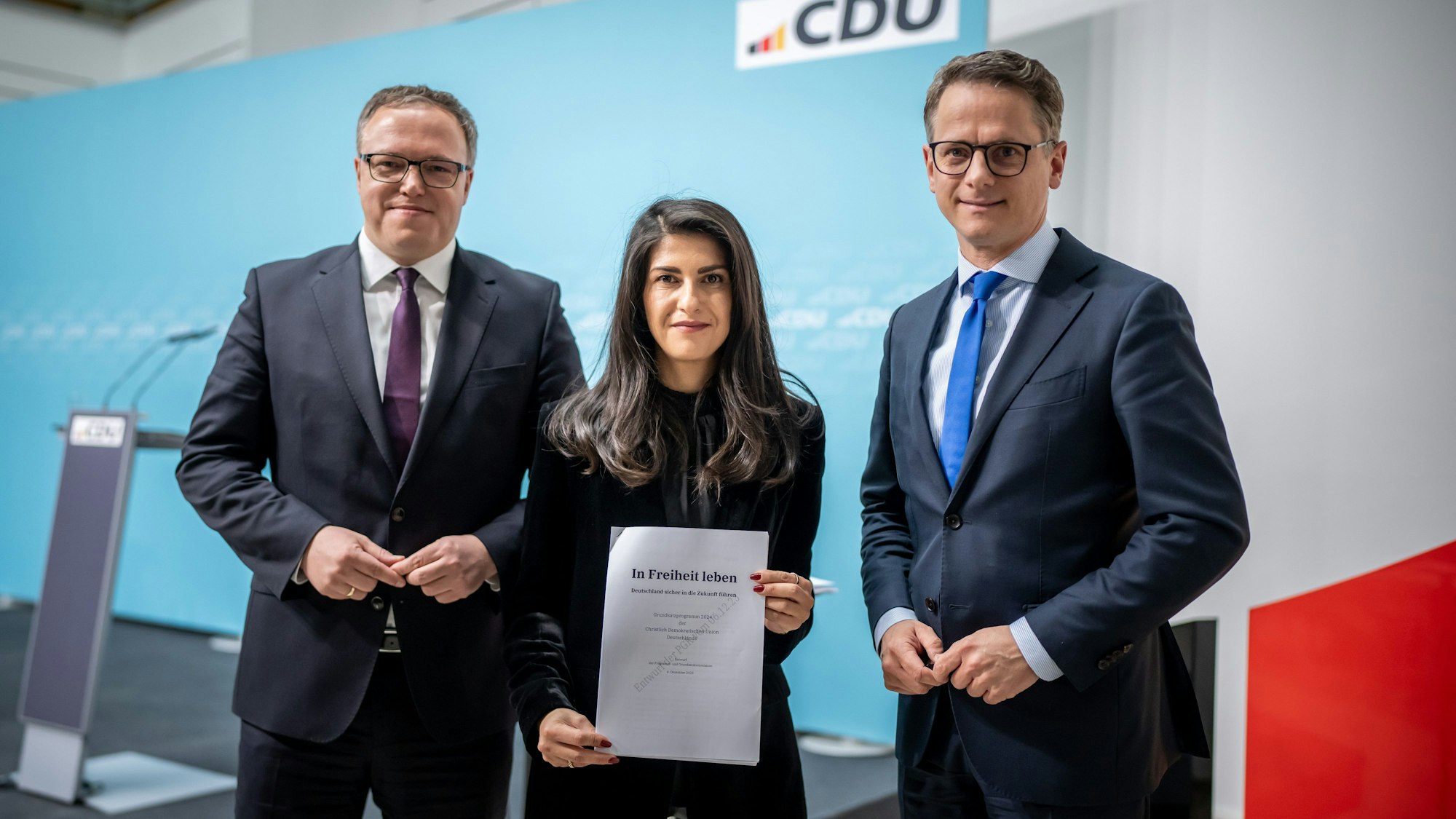 ARCHIV - 11.12.2023, Berlin: Carsten Linnemann (r), CDU-Generalsekretär und Vorsitzender der Programm- und Grundsatzkommission, und die stellvertretenden Vorsitzenden der Programm- und Grundsatzkommission, Serap Güler und Mario Voigt, nehmen an einer Pressekonferenz zum Entwurf der Kommission für ein neues Grundsatzprogramm der CDU teil und halten das entsprechende Dokument in der Hand. (zu dpa: «Bericht: CDU ändert umstrittenen Islam-Satz in Programmentwurf») Foto: Michael Kappeler/dpa +++ dpa-Bildfunk +++