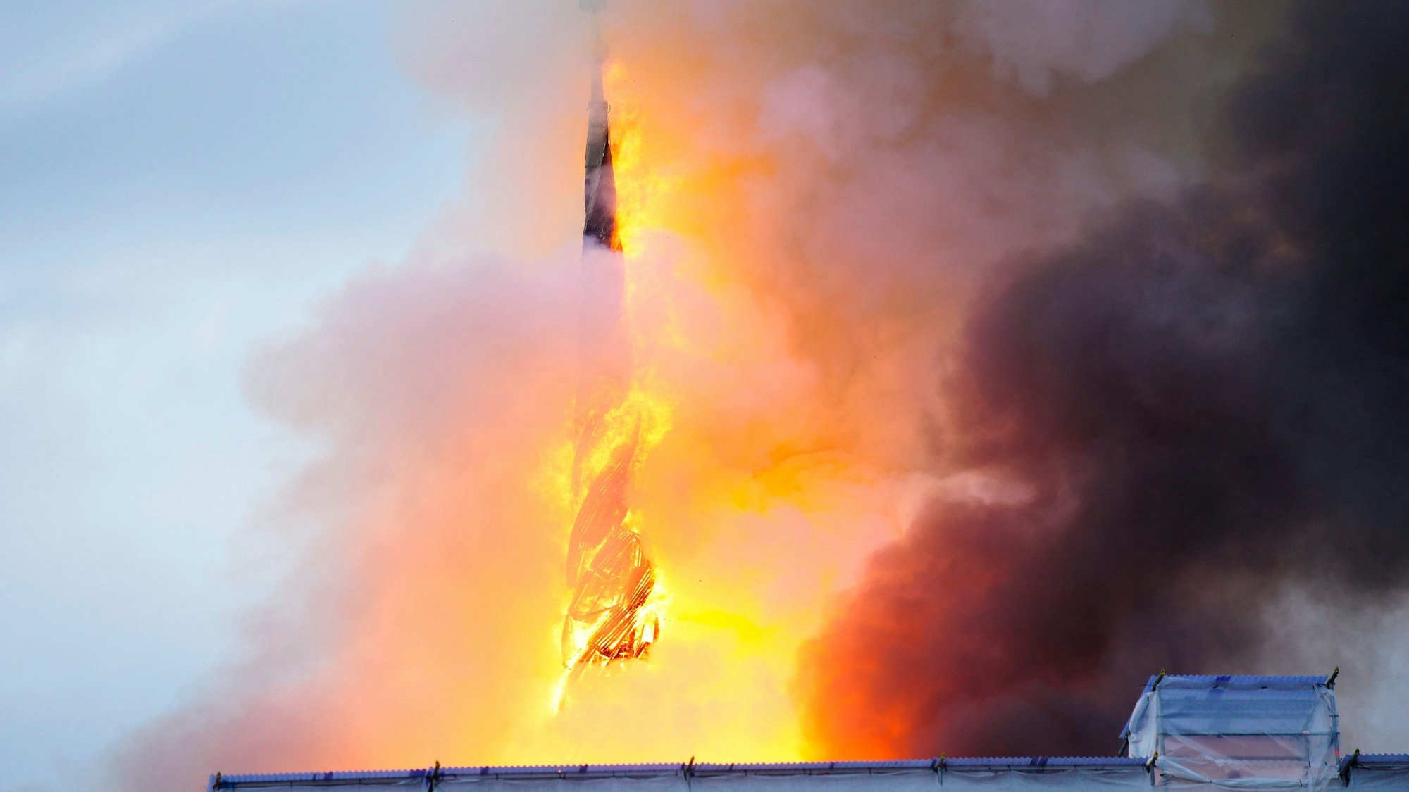 Eines der ältesten Gebäude Kopenhagens steht in Flammen, und seine ikonische Turmspitze ist eingestürzt.