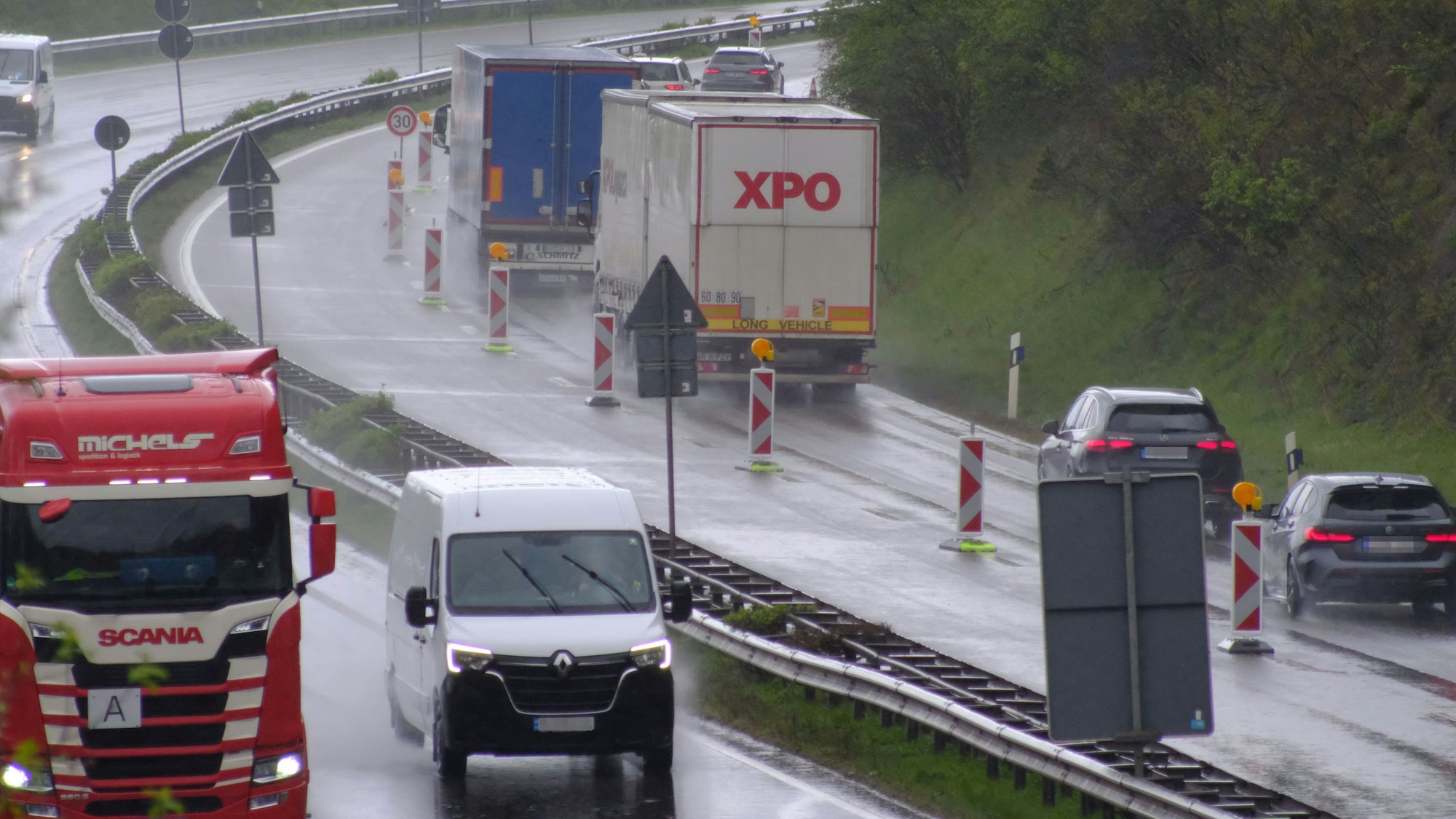 Lastwagen und Autos fahren auf der B51 bei Dahlem-Baasem. Die Fahrbahn ist regennass.