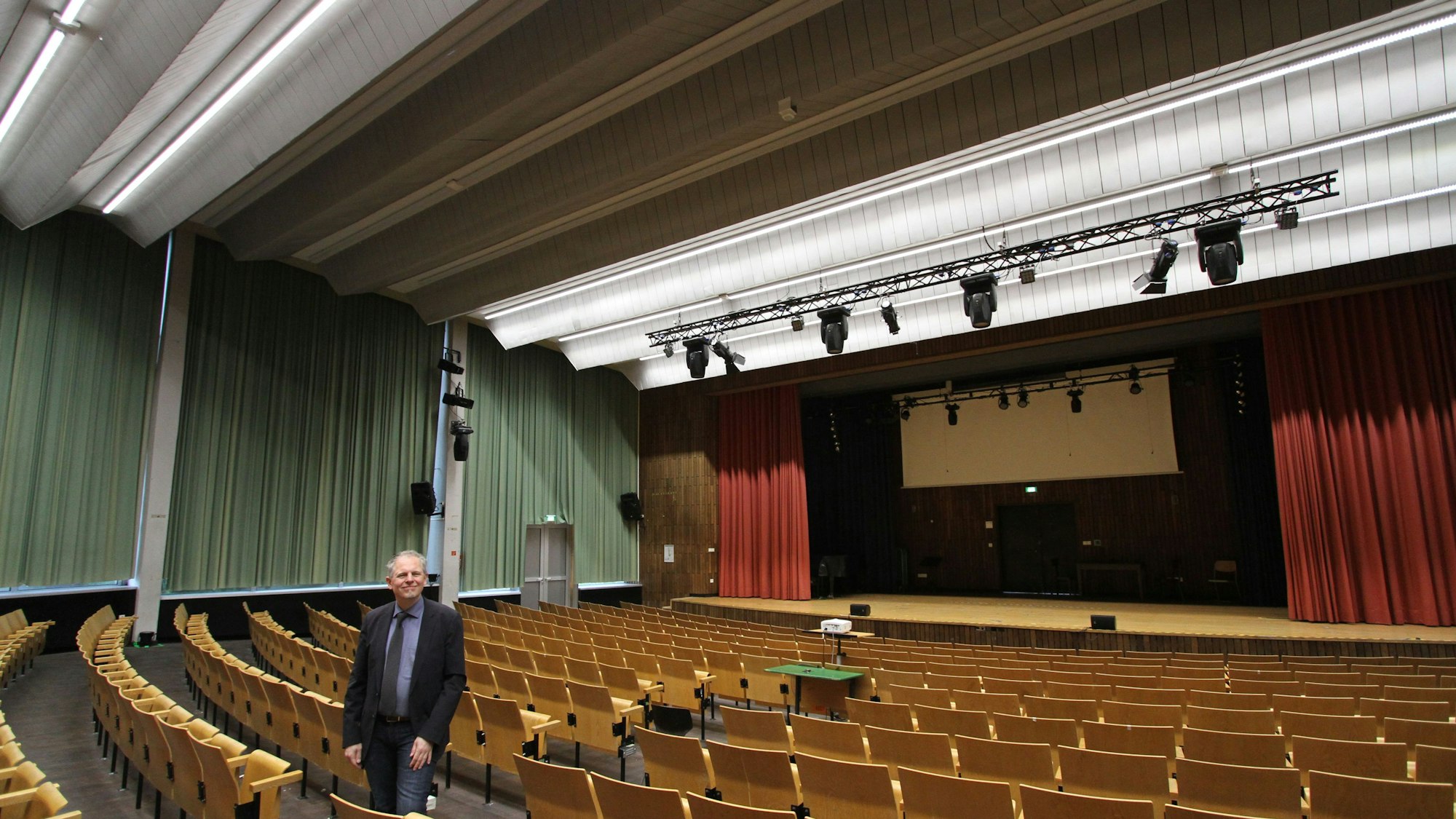 Ein Mann in einem großen Saal mit fester Bestuhlung