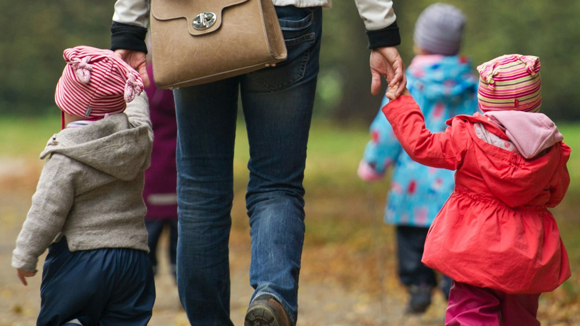 Eine Frau geht mit mehreren Kindern spazieren.