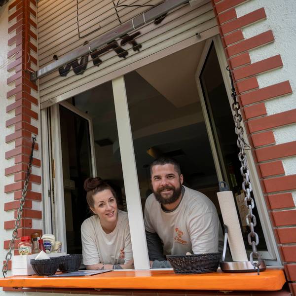 Ein Mann und eine Frau lehnen sich aus dem Fenster eines Restaurants.