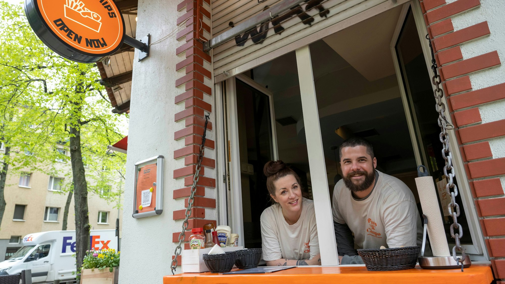 Ein Mann und eine Frau lehnen sich aus dem Fenster eines Restaurants.