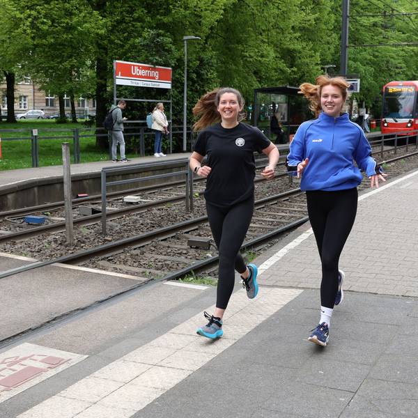 Die Kölnerinnen Katharina Oeltermann und Sophia Staudinger tragen Sportkleidung und laufen an der KVB-Haltestelle Ubierring entlang.
Foto von Martina Goyert