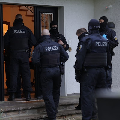 Polizeibeamte stehen an einem Gebäude, das durchsucht wird. Bei einer groß angelegten Razzia gegen eine international agierende Schleuserbande in acht Bundesländern hat die Staatsanwaltschaft Düsseldorf zehn Verdächtige verhaften lassen. Bei dem Einsatz waren seit dem frühen Morgen mehr als 1000 Beamte der Bundespolizei und der Staatsanwaltschaft beteiligt. Insgesamt wurden 101 Wohn- und Geschäftsräume durchsucht.