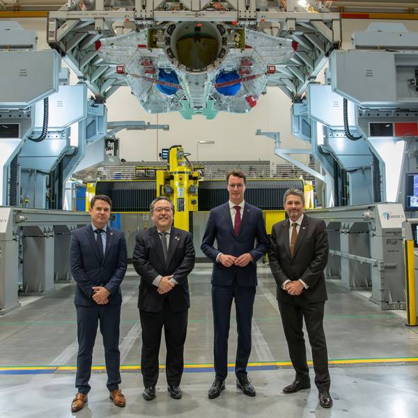 Hendrik Wüst und Industrievertreter sind in einem Werk im Gruppenbild zu sehen.