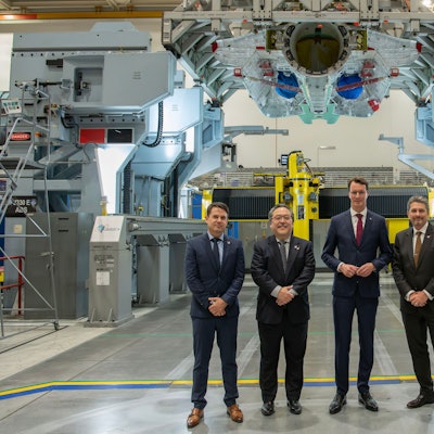 Hendrik Wüst und Industrievertreter sind in einem Werk im Gruppenbild zu sehen.