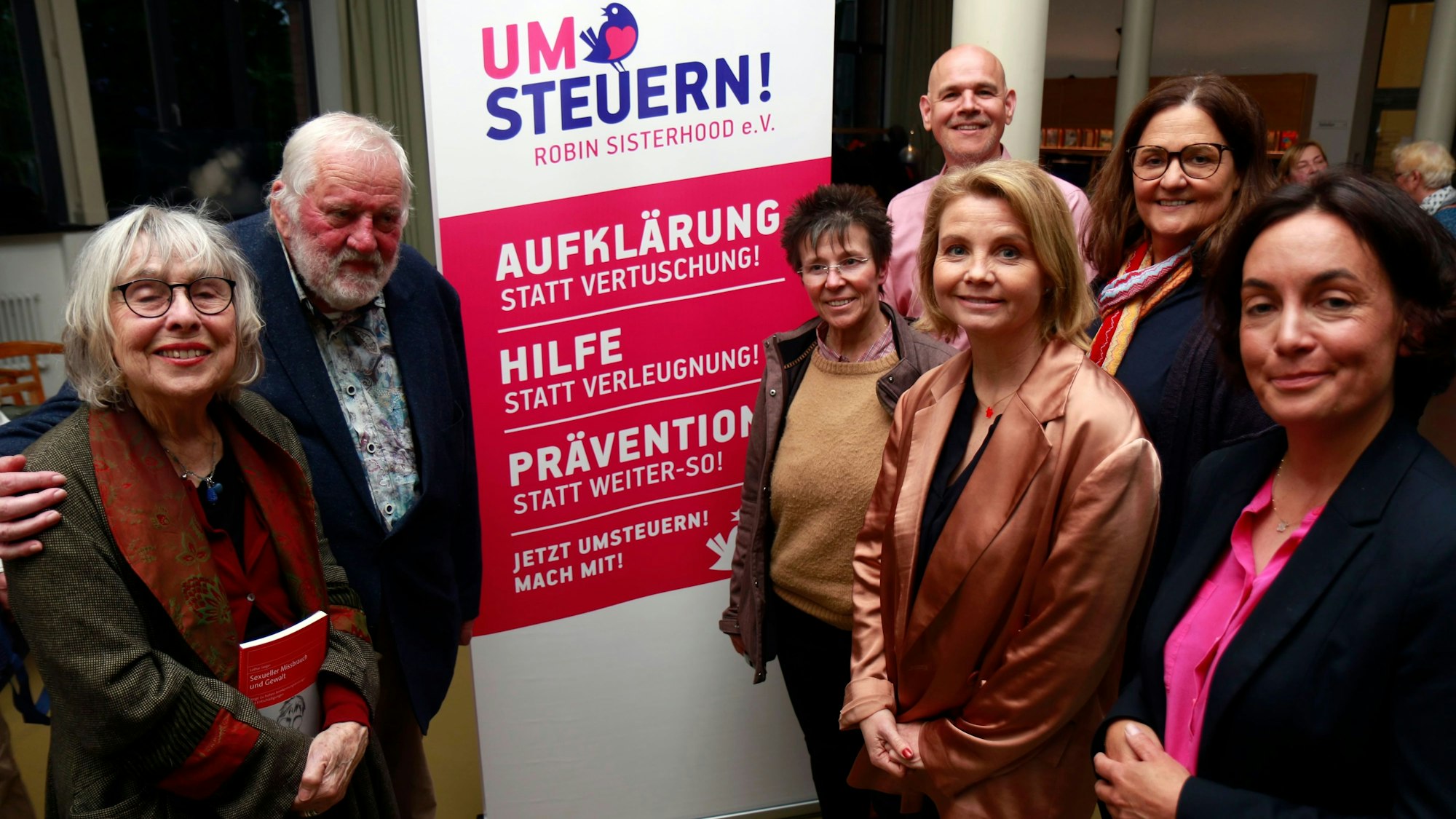 Sieben Personen stehen neben einem Schild „Umsteuern - Robin Sisterhood e.V.“