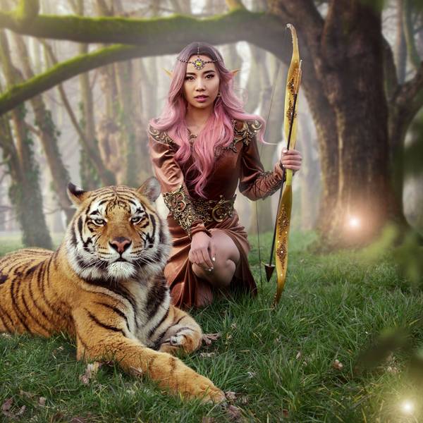 Eine Frau trägt Elfenohren und posiert mit einem ausgewachsenem Tiger.