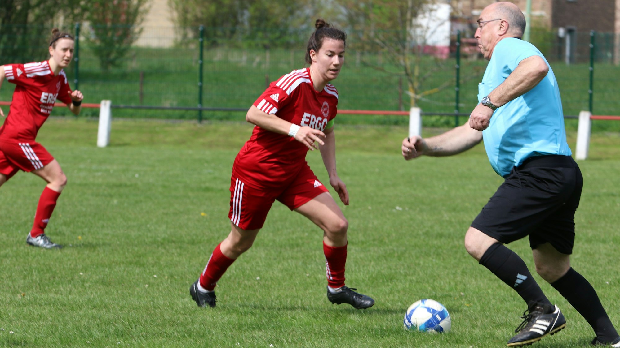 Der Schiedsrichter steht einer Fußballspielerin im Weg und muss schnell beiseite springen.