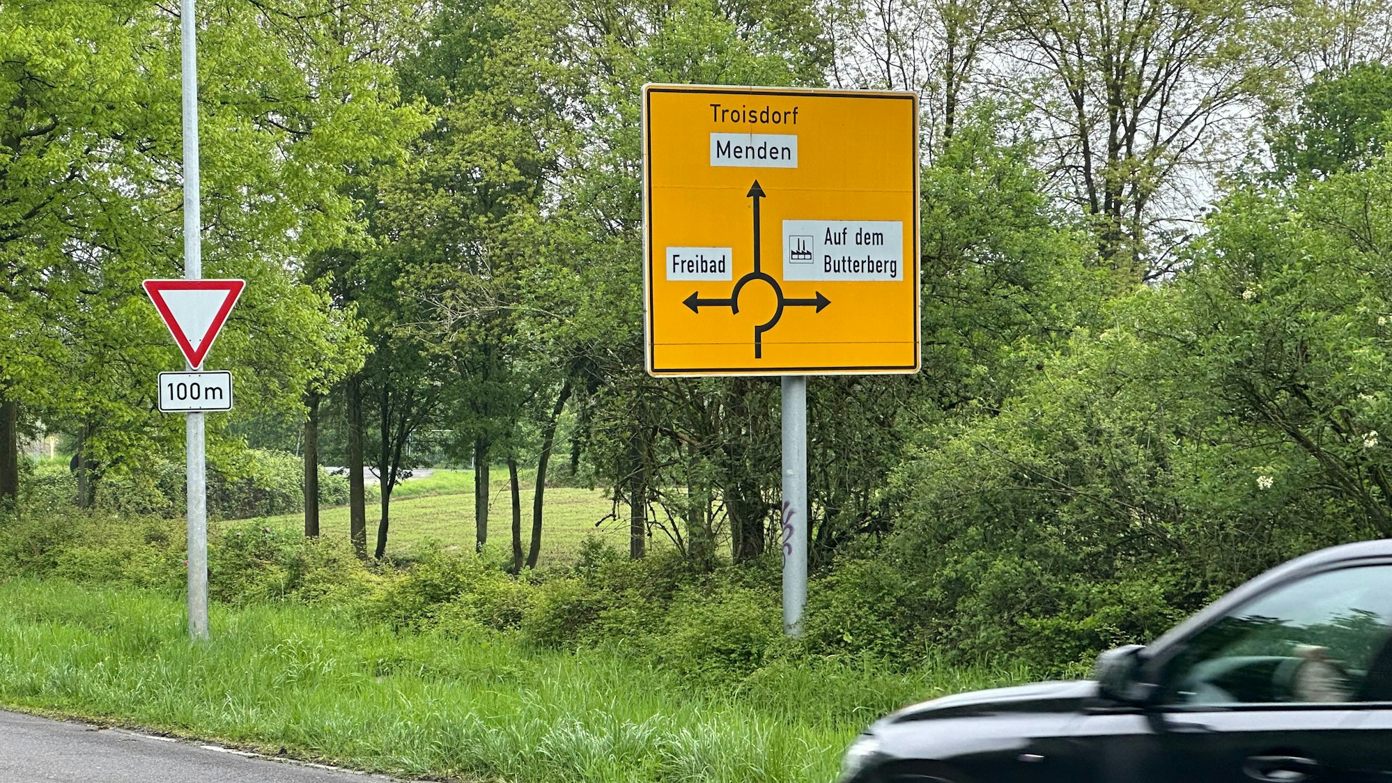 Ein gelbes Straßenschild an einem Kreisverkehr.