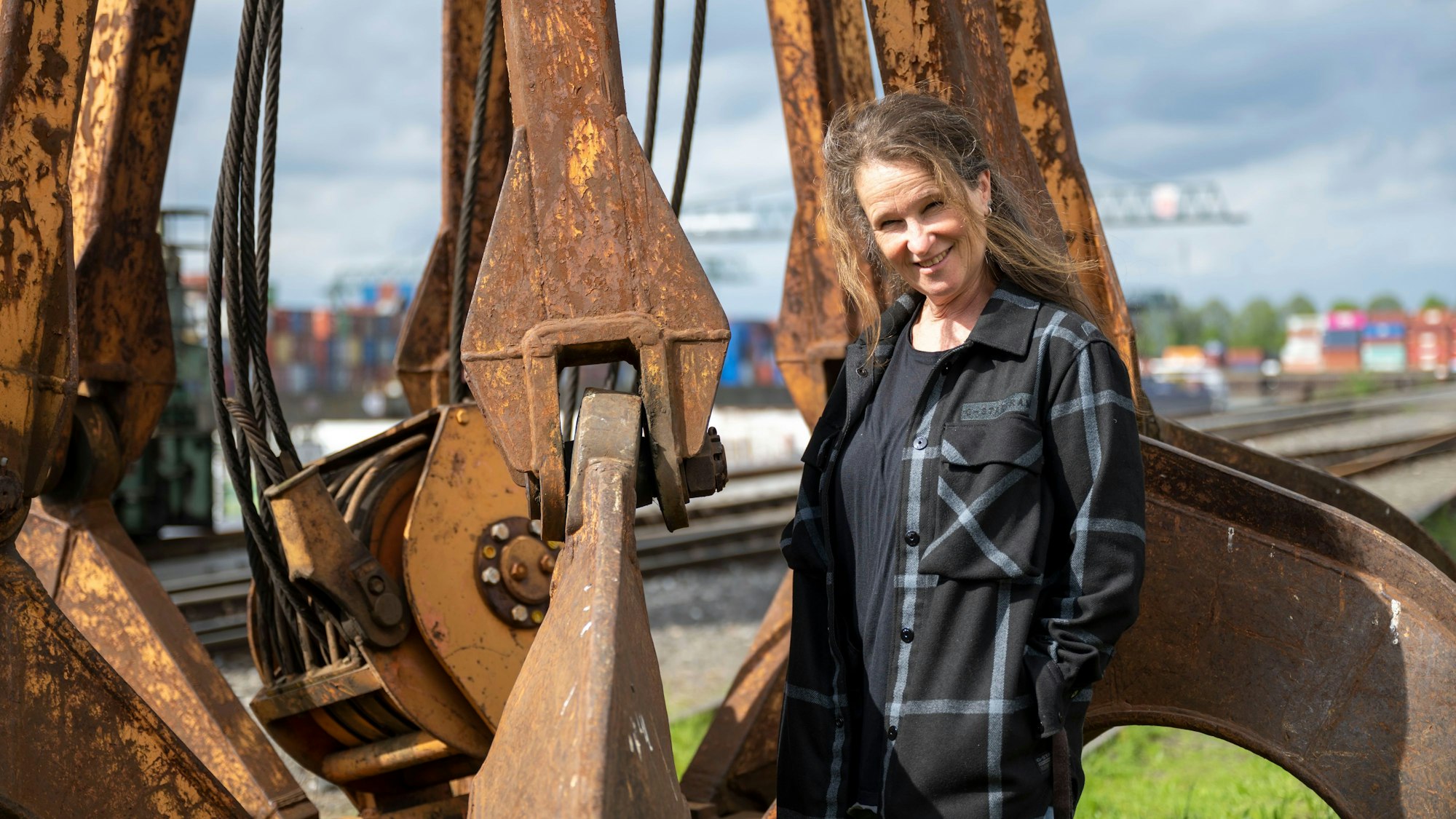 Frau steht am Niehler Hafen vor einem Kran.