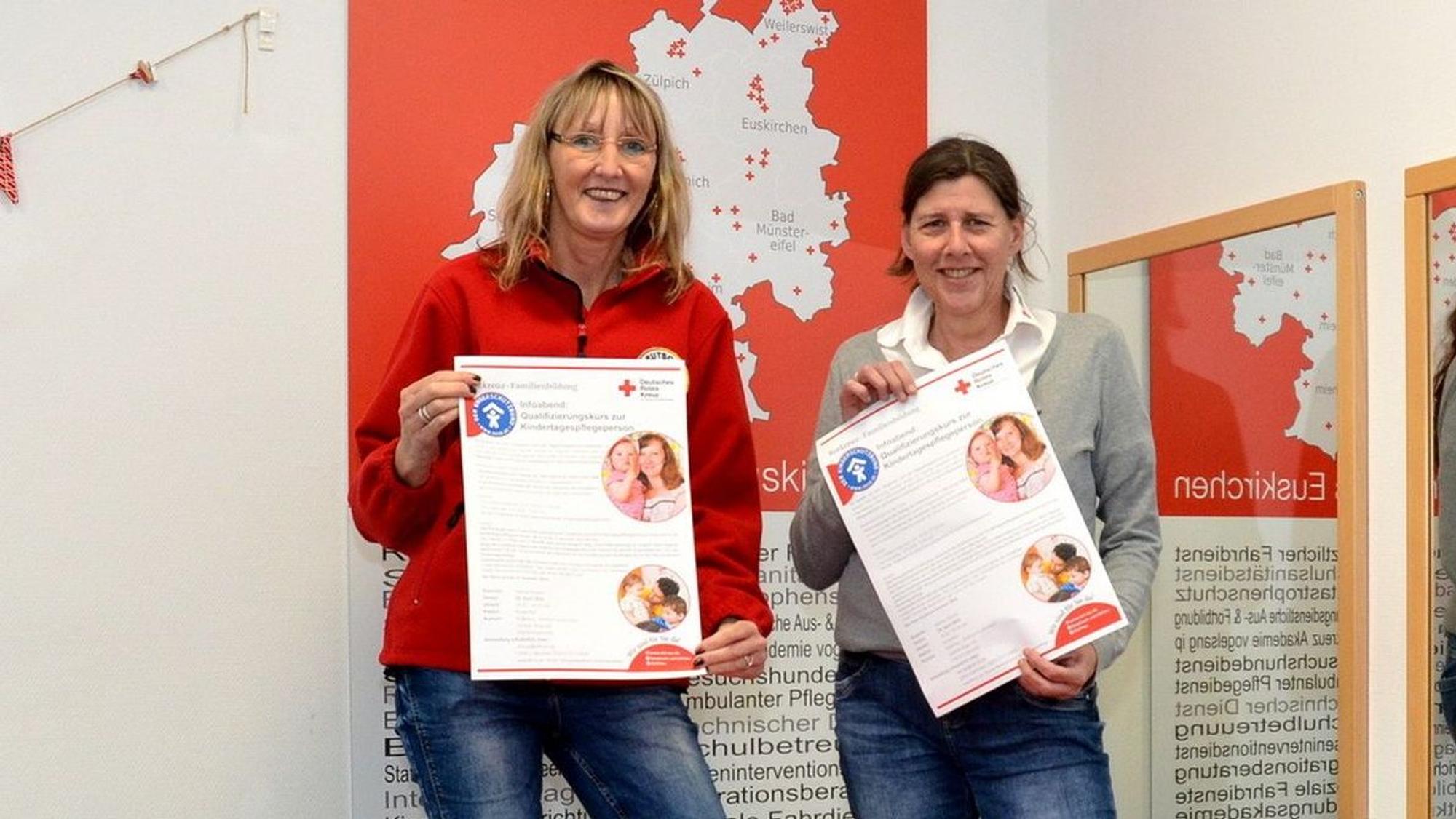 Heike Iven und Sabine Heines halten Plakate, auf denen für die Qualifizierungsmaßnahme geworben wird, hoch.