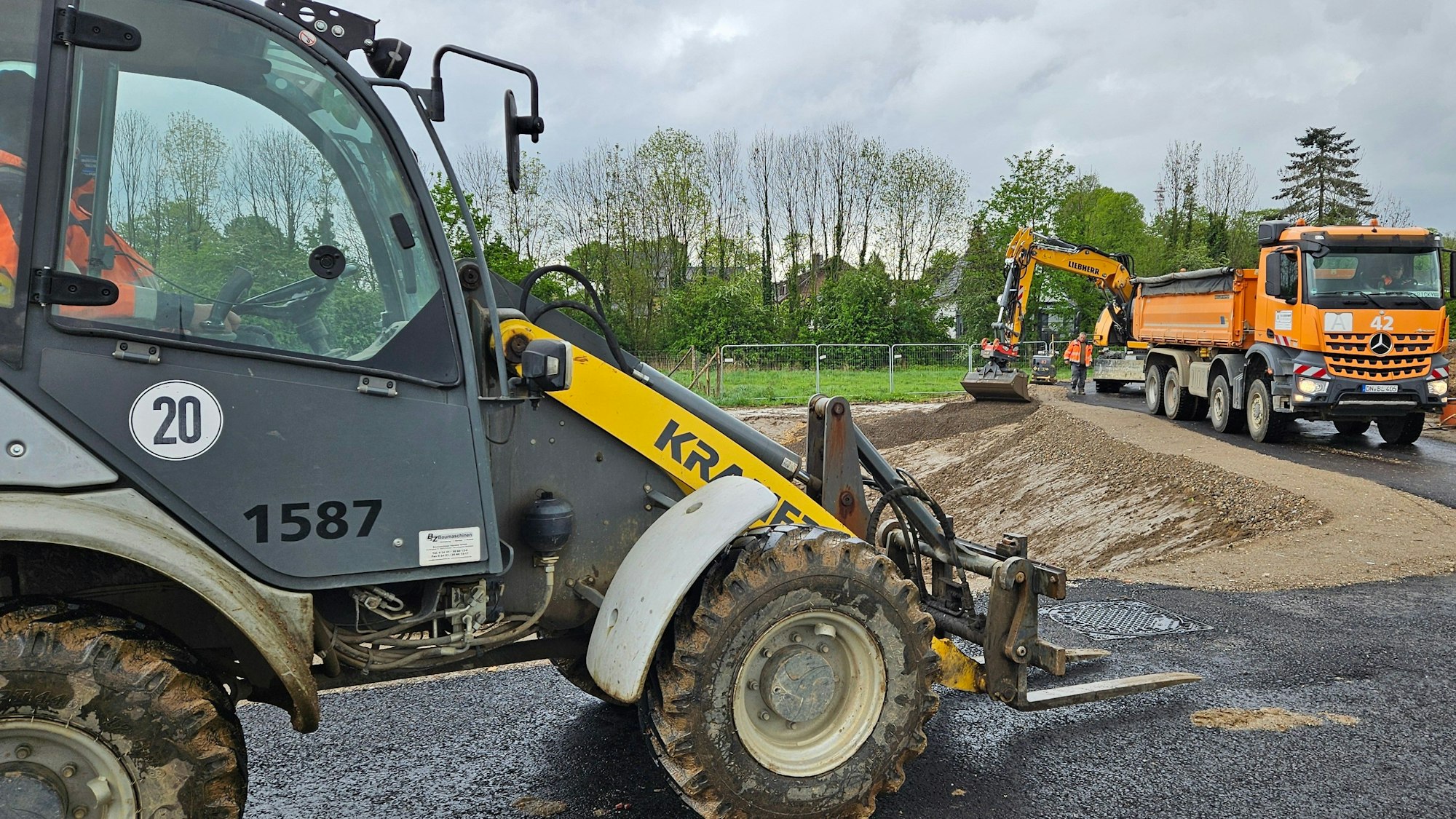 Ein Bagger und andere Baufahrzeuge stehen in einem Neubaugebiet.