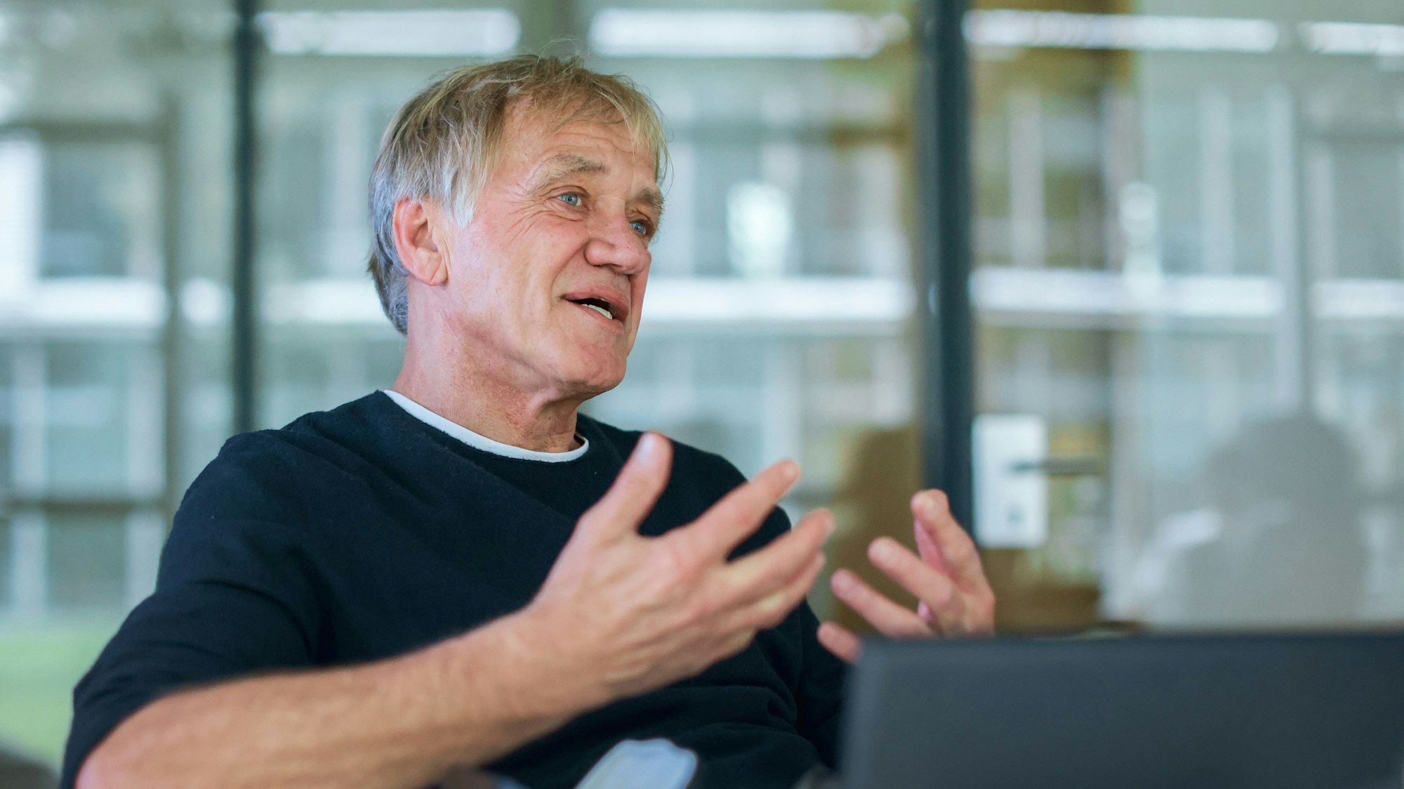Norbert Oberhaus sitzt hinter einem Laptop und gestikuliert mit den Armen.