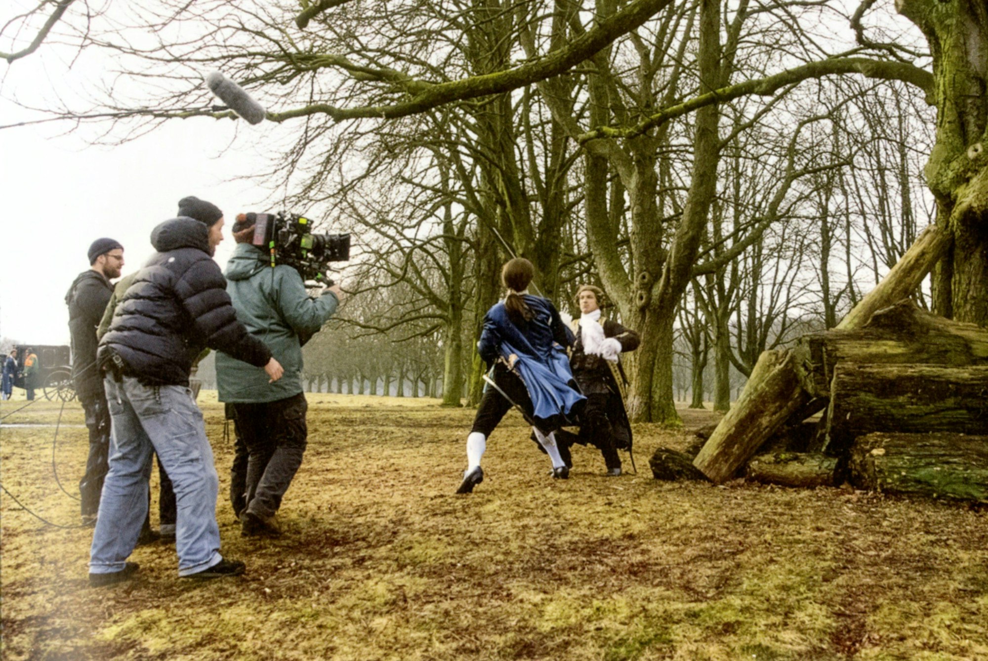 Männer in historischen Kostümen fechten im Park.