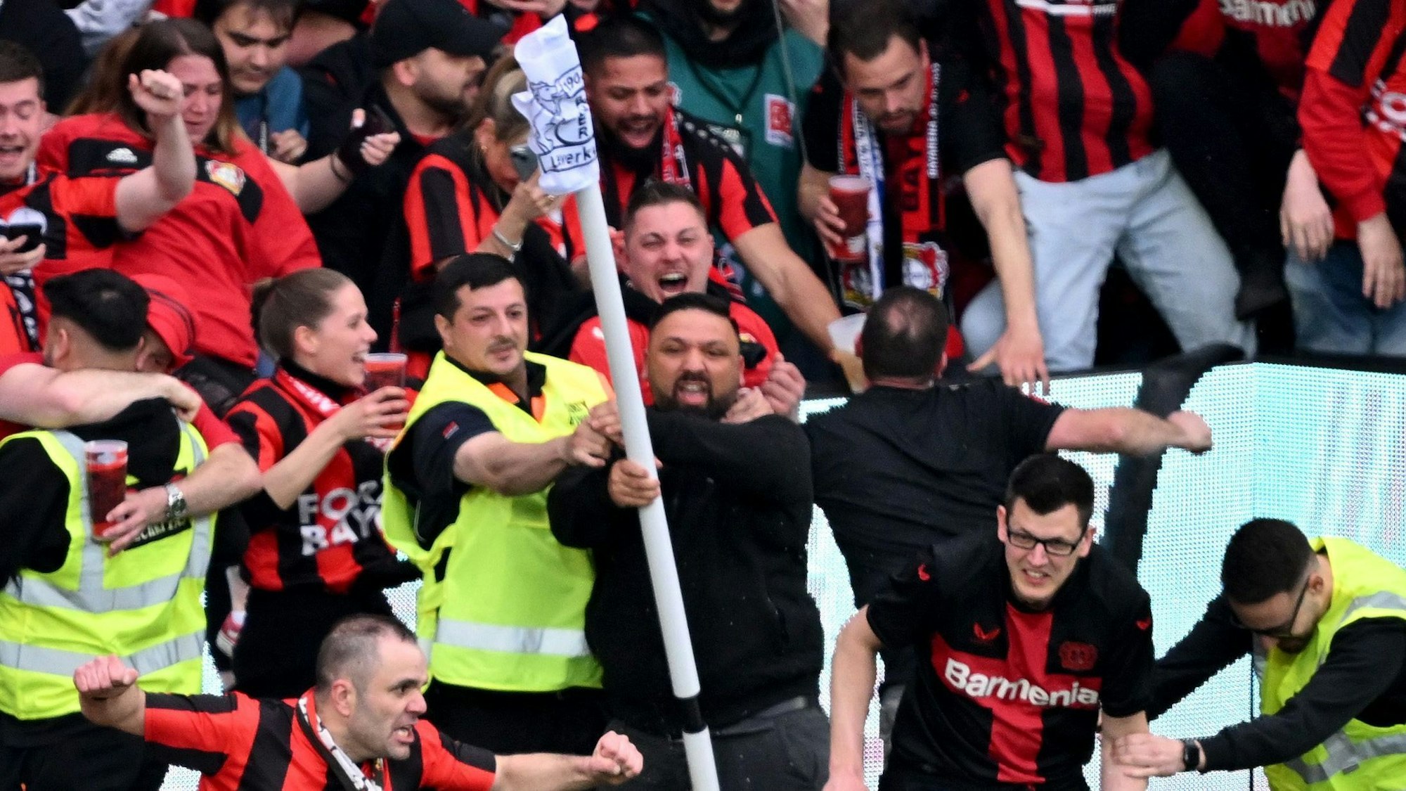 Die Ordner der BayArena haben nach dem 4:0 gegen Bremenl mit den stürmenden Fans alle Hände voll zu tun. Ein Ordner versucht einen Fan davon abzuhalten, die Eckfahne abzureißen.