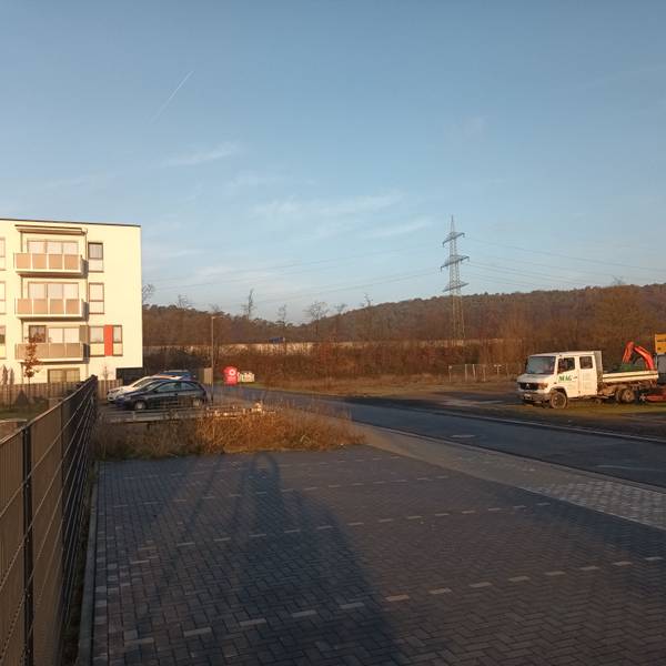 Ein Haus, eine Straße und eine Freifläche mit Baumaschinen