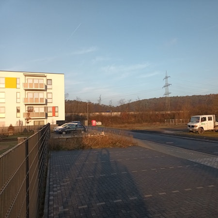 Ein Haus, eine Straße und eine Freifläche mit Baumaschinen