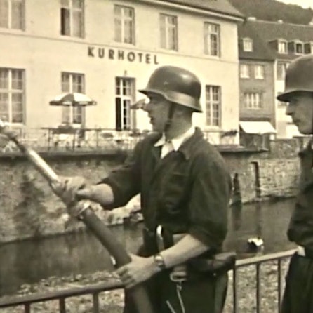 Zwei Feuerwehrleute stehen vor dem ehemaligen Kurhotel, einer hält einen Schlauch.