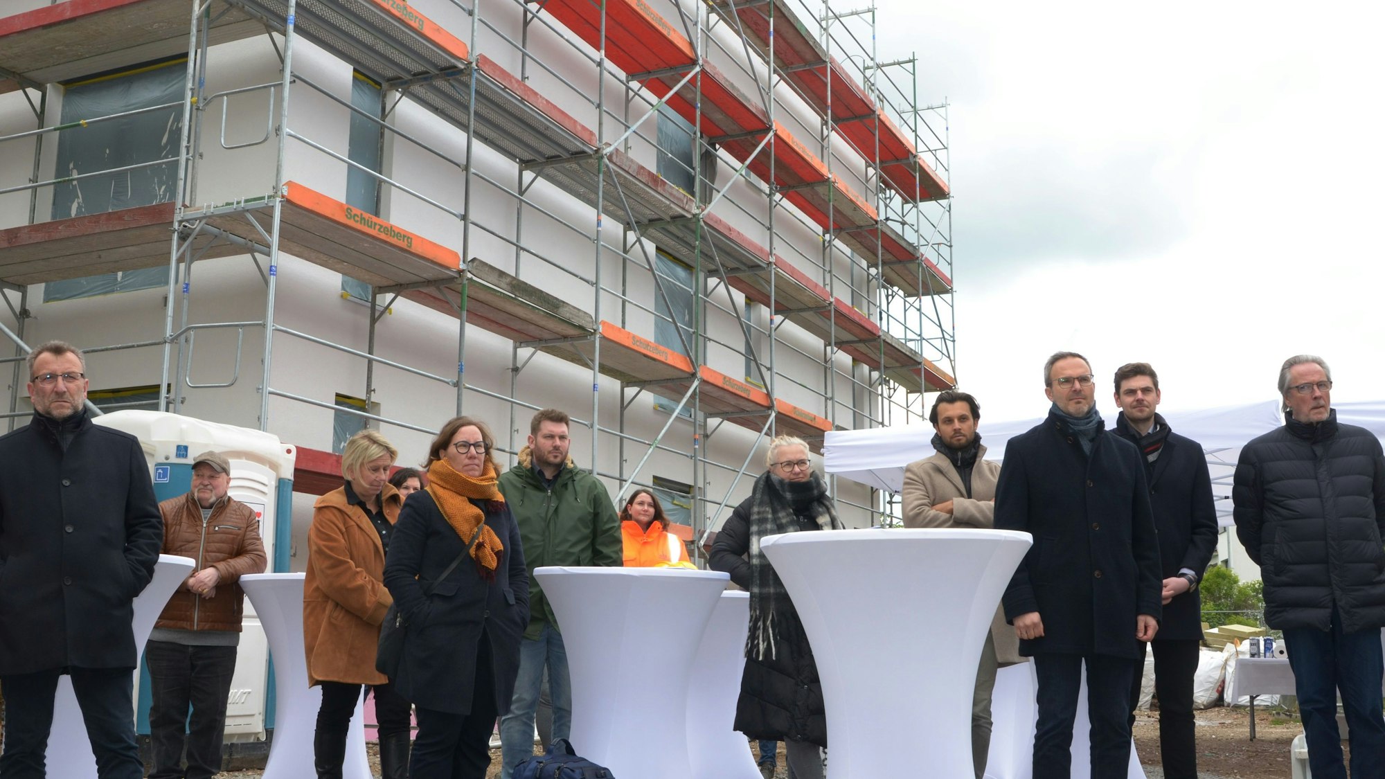 Einige der Festteilnehmer stehen vor einem der neuen Häuser, die noch eingerüstet sind.