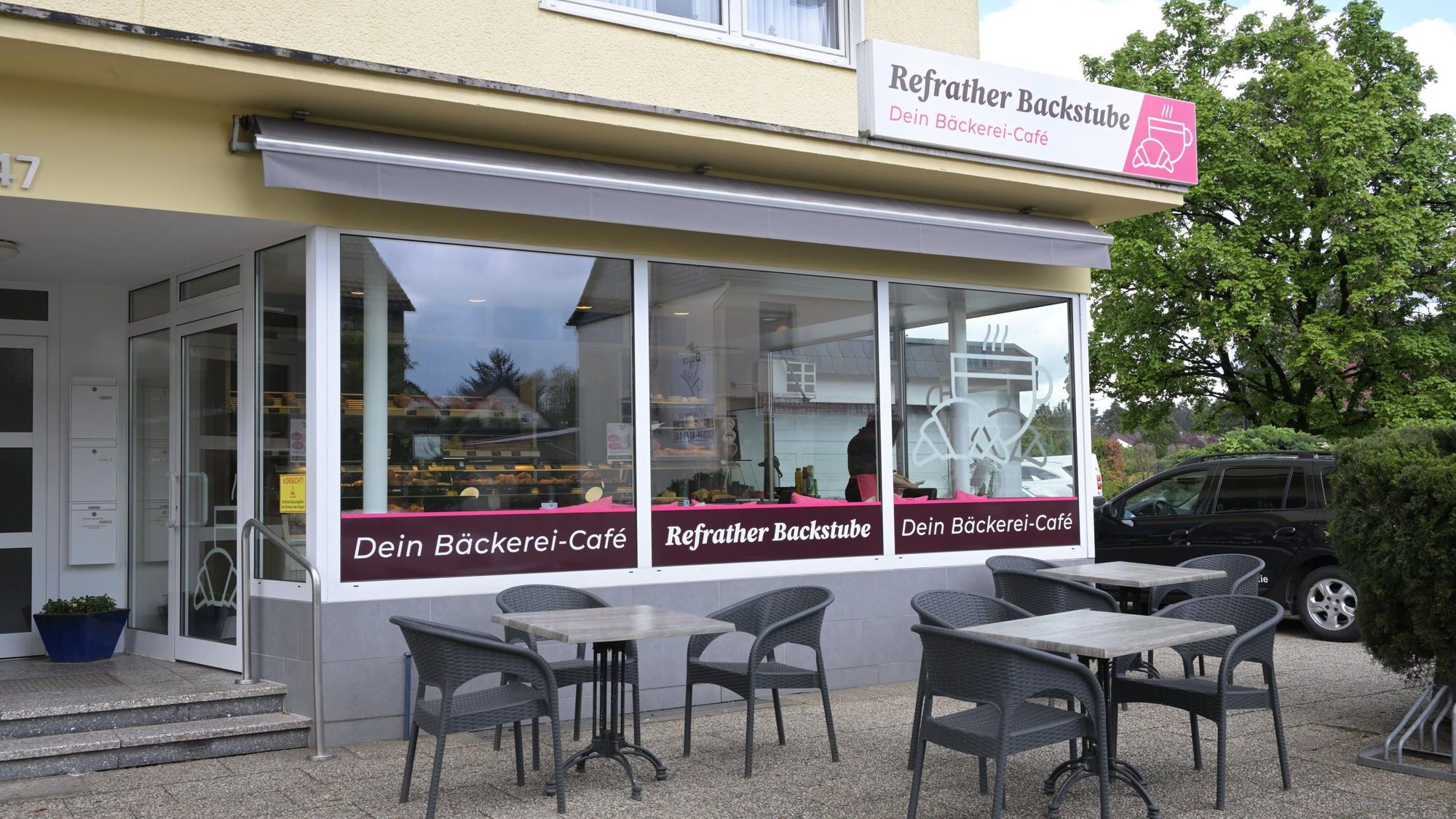 Zu sehen ist die Außenansicht der Bäckerei mit drei Tischen sowie Stühlen vor dem Geschäft.