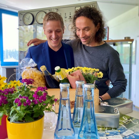 Landrat Markus Ramers und Stephan Brings stehen Arm in Arm vor einer „Eifel Kiste“.