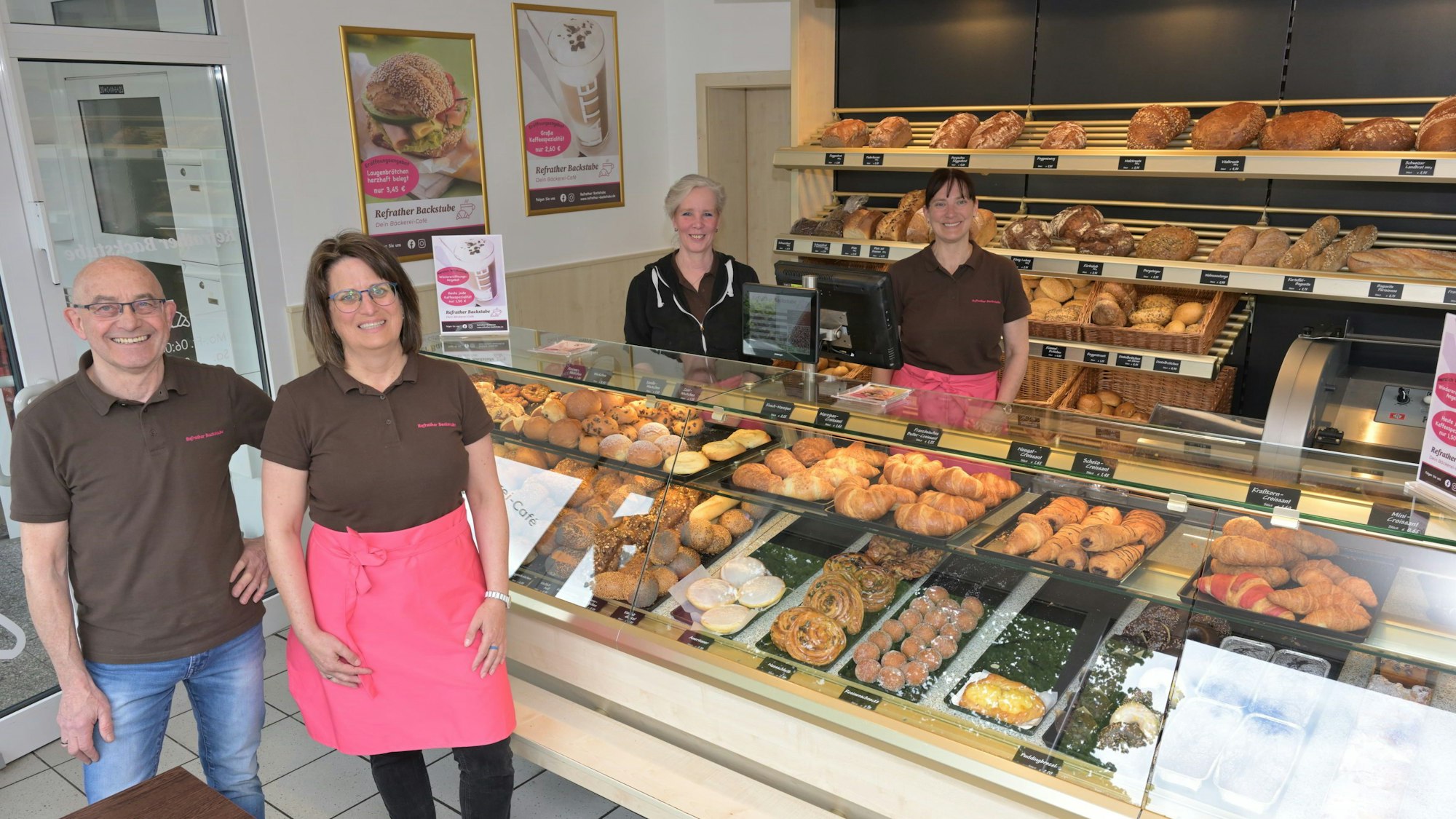 Vor der Theke im neuen Geschäft steht das Ehepaar, dahinter zwei Mitarbeiterinnen