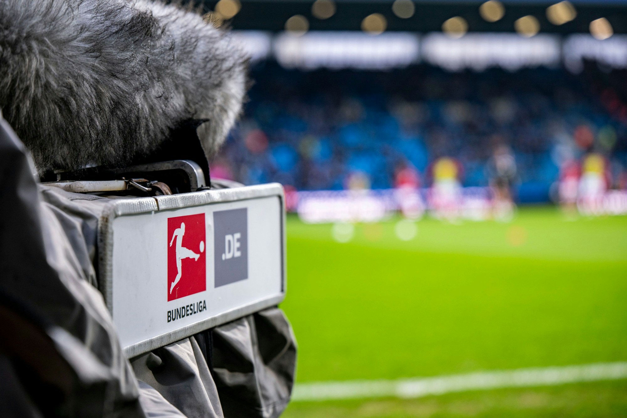 Ein Kameramann filmt vor dem Spiel das Aufwärmen auf dem Spielfeld.