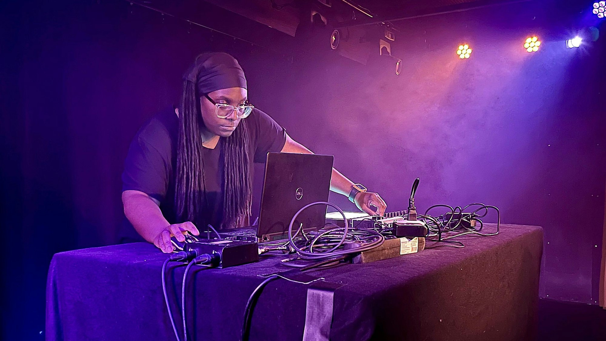 Jlin auf der Bühne des Jaki im Kölner Stadtgarten. Sie trägt eine schwarze Bandana und ein schwarzes T-Shirt, beugt sich über ihren Laptop.