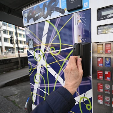 Ein Mann zieht seinen Ausweis durch den Schlitz eines Zigarettenautomaten. Ein solcher ist in Köln-Vingst gesprengt worden. (Symbolbild)