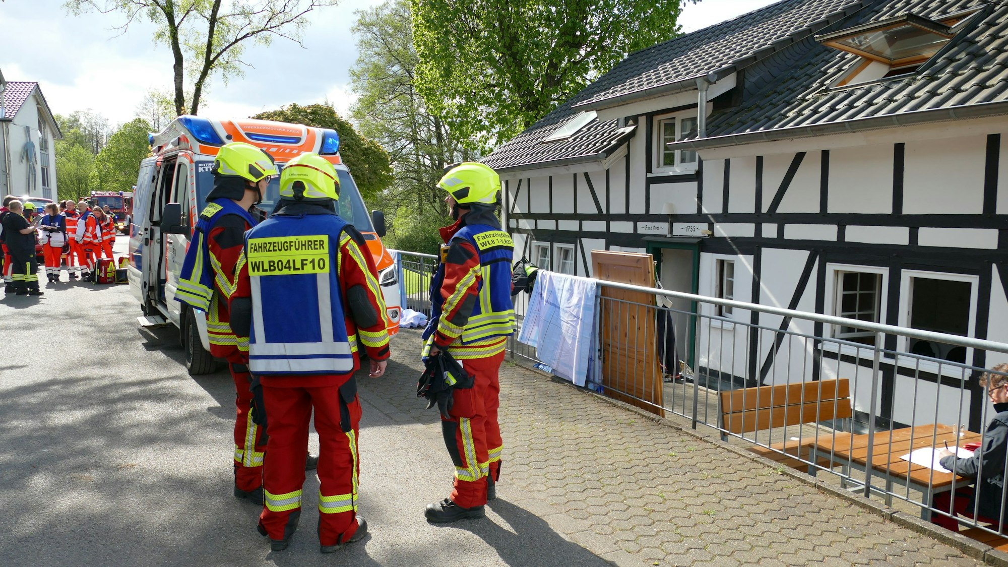 Feuerwehrleute stehen vor einem Fachwerkhaus, in dem es zuvor gebrannt hat.
