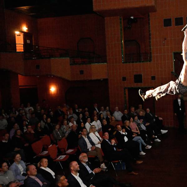 Ein Mann hängt an einer Laterne über dem Publikum im großen Saal des Bergischen Löwen.