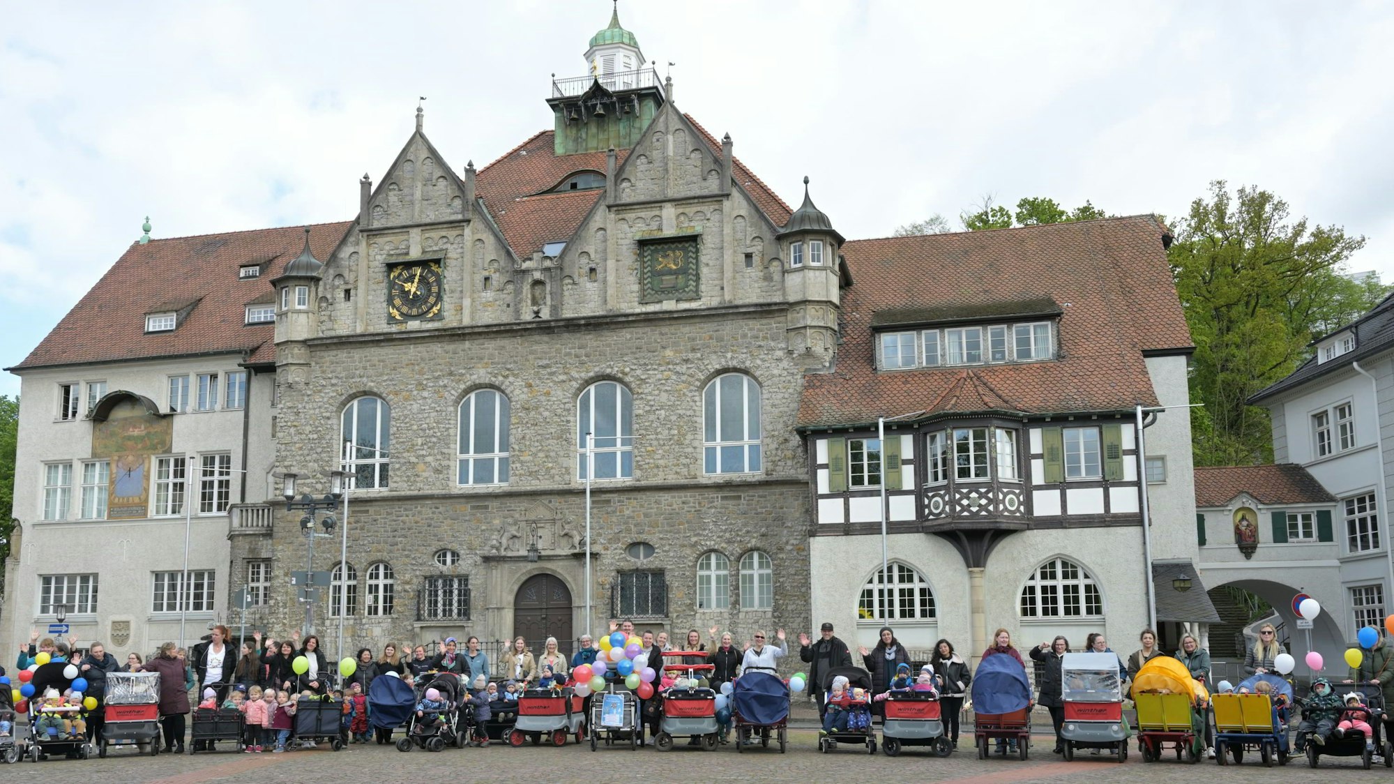 Vor dem Rathaus in Bergisch Gladbach stehen Eltern und Tageseltern mit ihren Kindern.