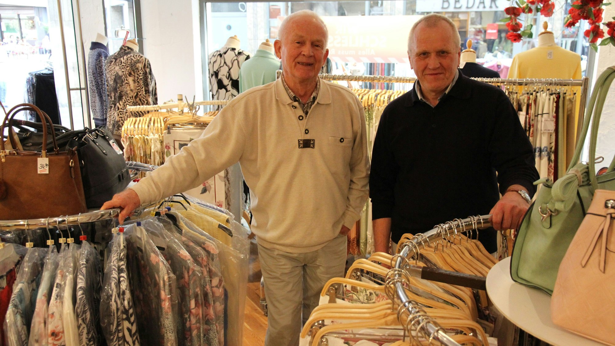 Zwei Männer neben Warenständern in einem Textilgeschäft