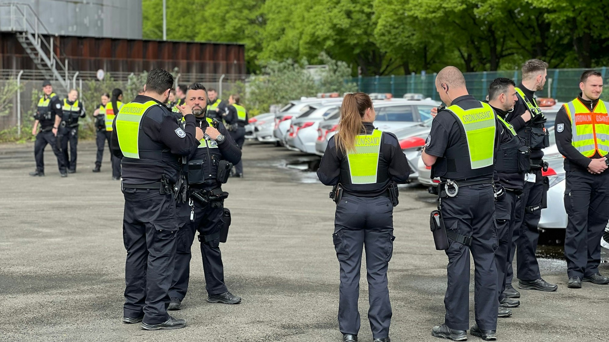Mitarbeiterinnen und Mitarbeiter des Kölner Ordnungsamt stehen auf einem Parkplatz im Niehler Industriegebiet.