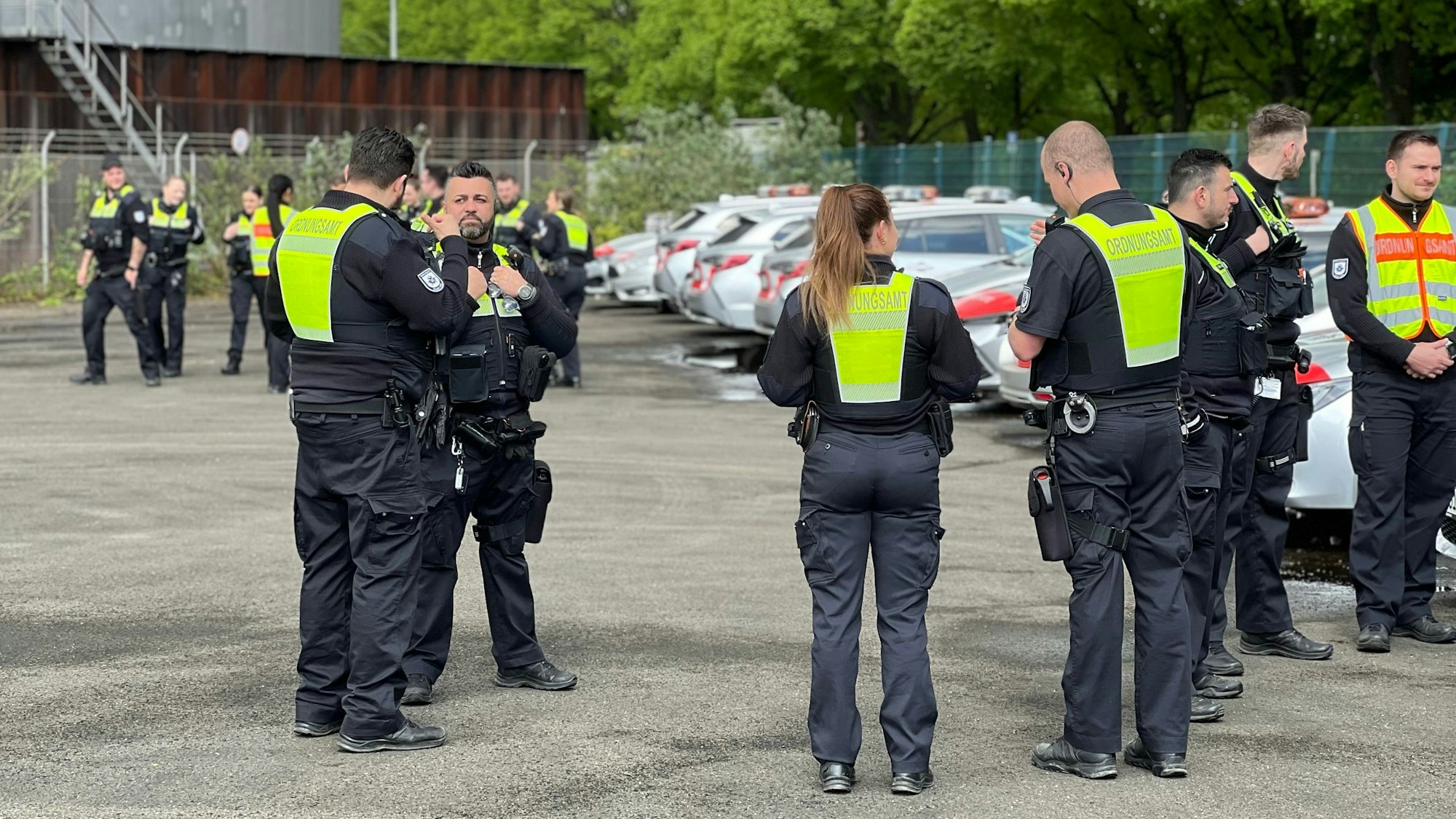 Einsatzkräfte des Ordnungsamts stehen auf einem Parkplatz.