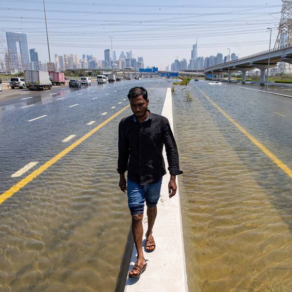 Ein Mann läuft über eine Mauer zwischen zwei überfluteten Straßen in Dubai. Experten halten Cloud Seeding nicht für den Grund für die heftigen Regenfälle in den Vereinigten Arabischen Emiraten.