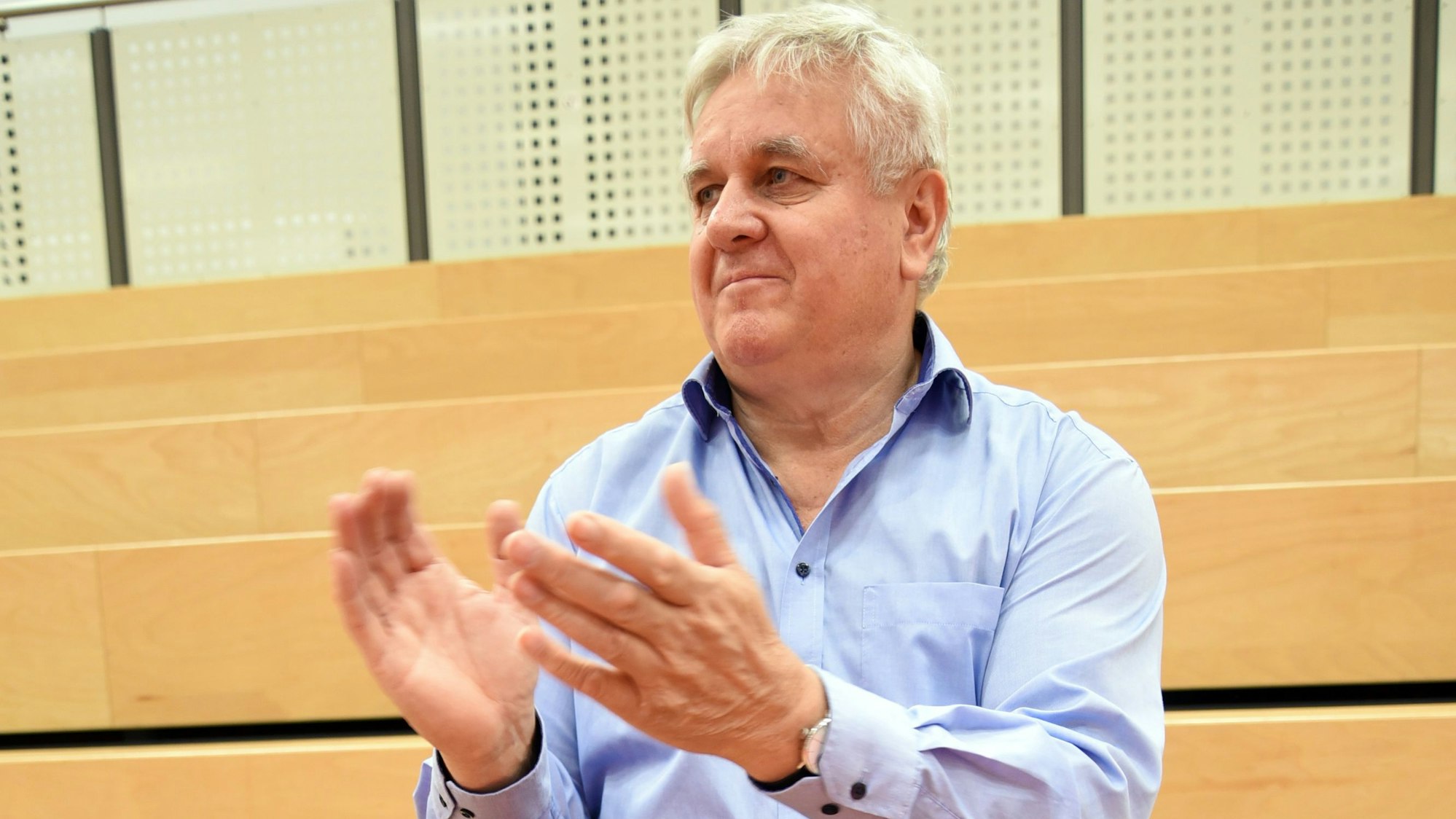 Andreas Lamsfuß sitzt auf einer Tribüne und applaudiert.