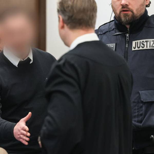 Der 27-jährige Angeklagte begrüßt seinen Verteidiger beim Prozessauftakt im Landgericht Köln.