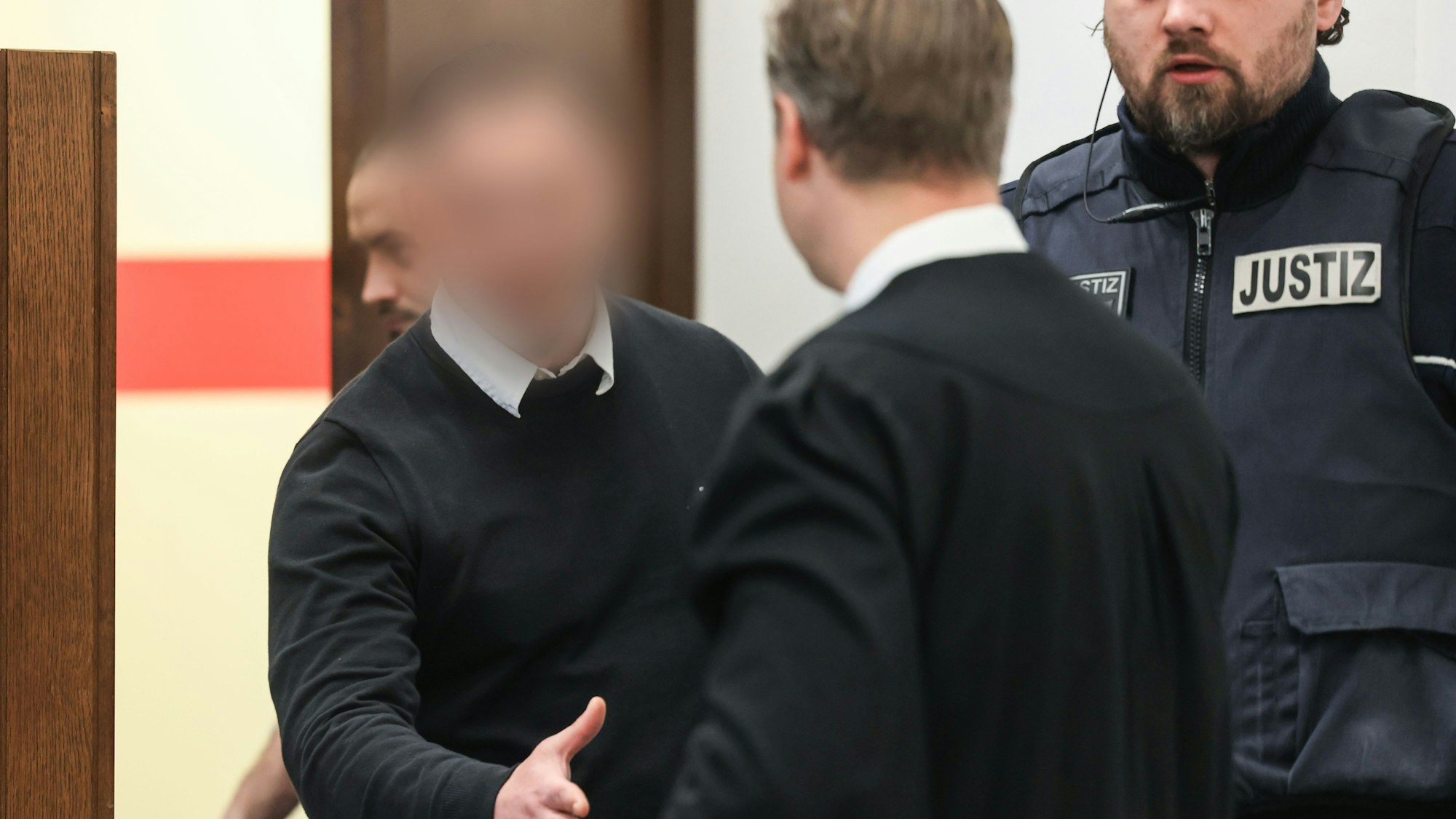 Der 27-jährige Angeklagte begrüßt seinen Verteidiger beim Prozessauftakt im Landgericht Köln.