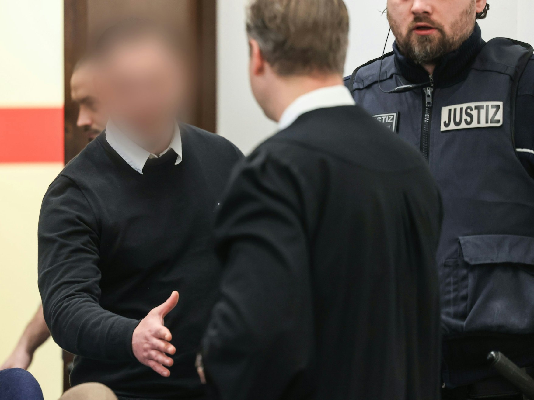 Der Angeklagte Hami S. (27) begrüßt seinen Verteidiger beim Prozessauftakt im Landgericht Köln.