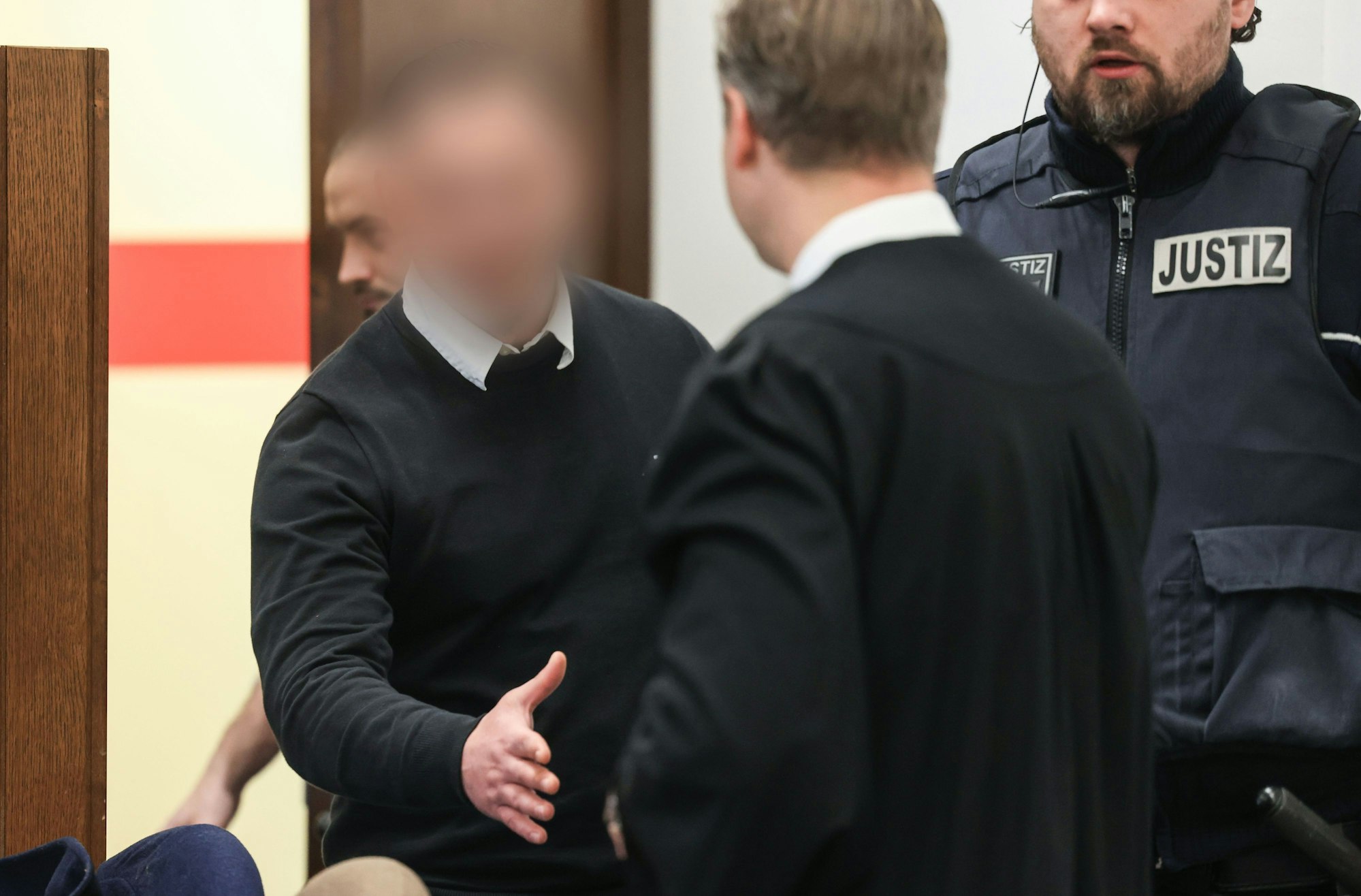 Der 27-jährige Angeklagte begrüßt seinen Verteidiger beim Prozessauftakt im Landgericht Köln.