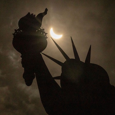 8, April 2024,  USA, New York: Der Mond verdeckt teilweise die Sonne hinter der Freiheitsstatue während der totalen Sonnenfinsternis auf Liberty Island.