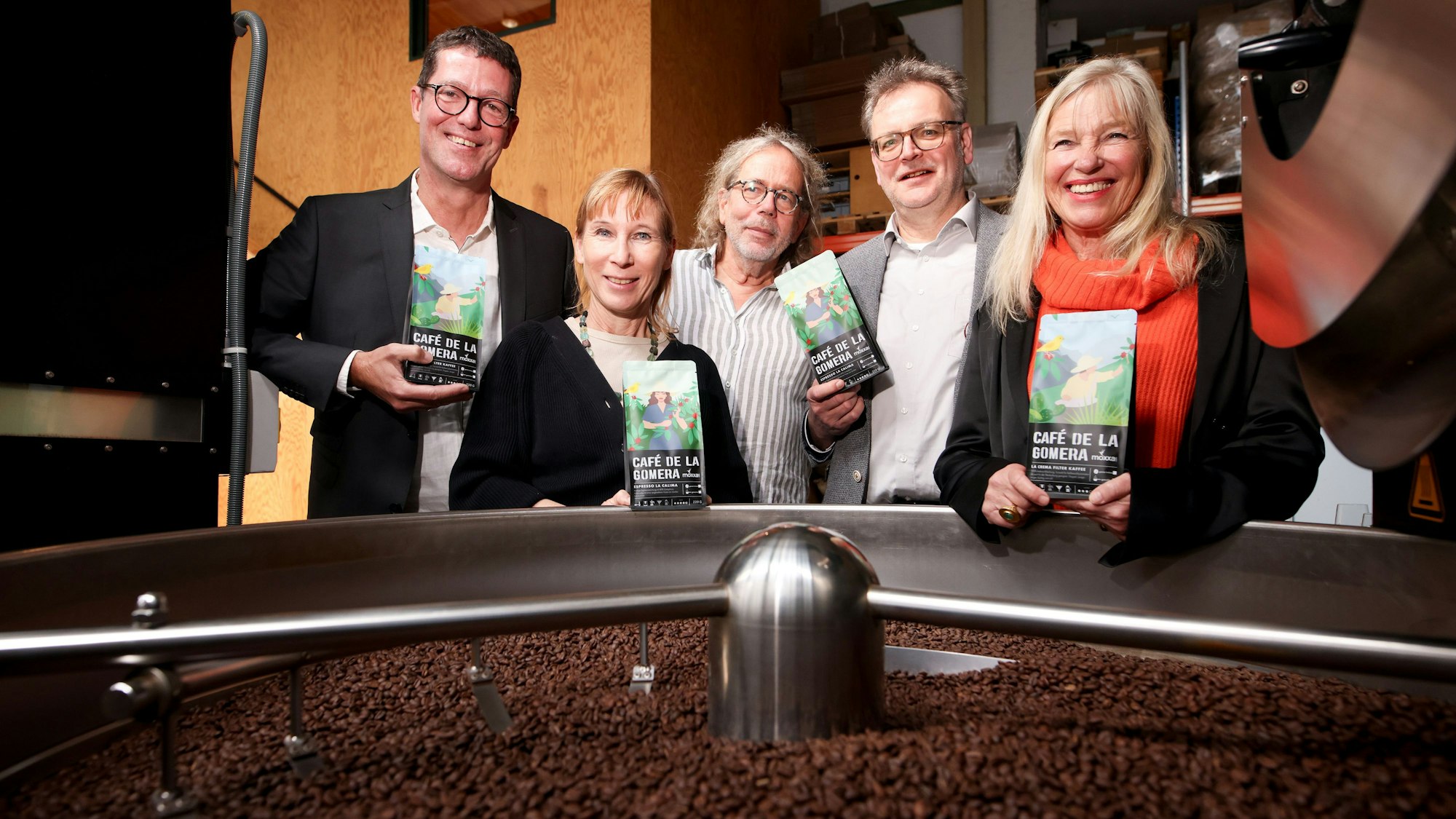 Fünf Menschen stehen an Kaffeeröster