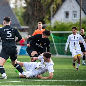 Das Bild zeigt die JSG Erft in schwarzen Trikots, wie sie mit viel Einsatz einen Torschuss versucht zu verhindern.