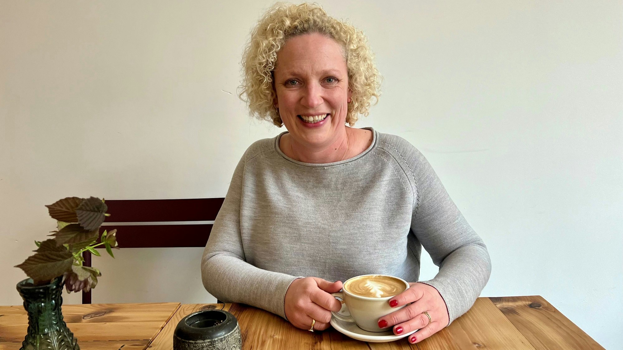Blonde Frau mit Cappuccino im Café