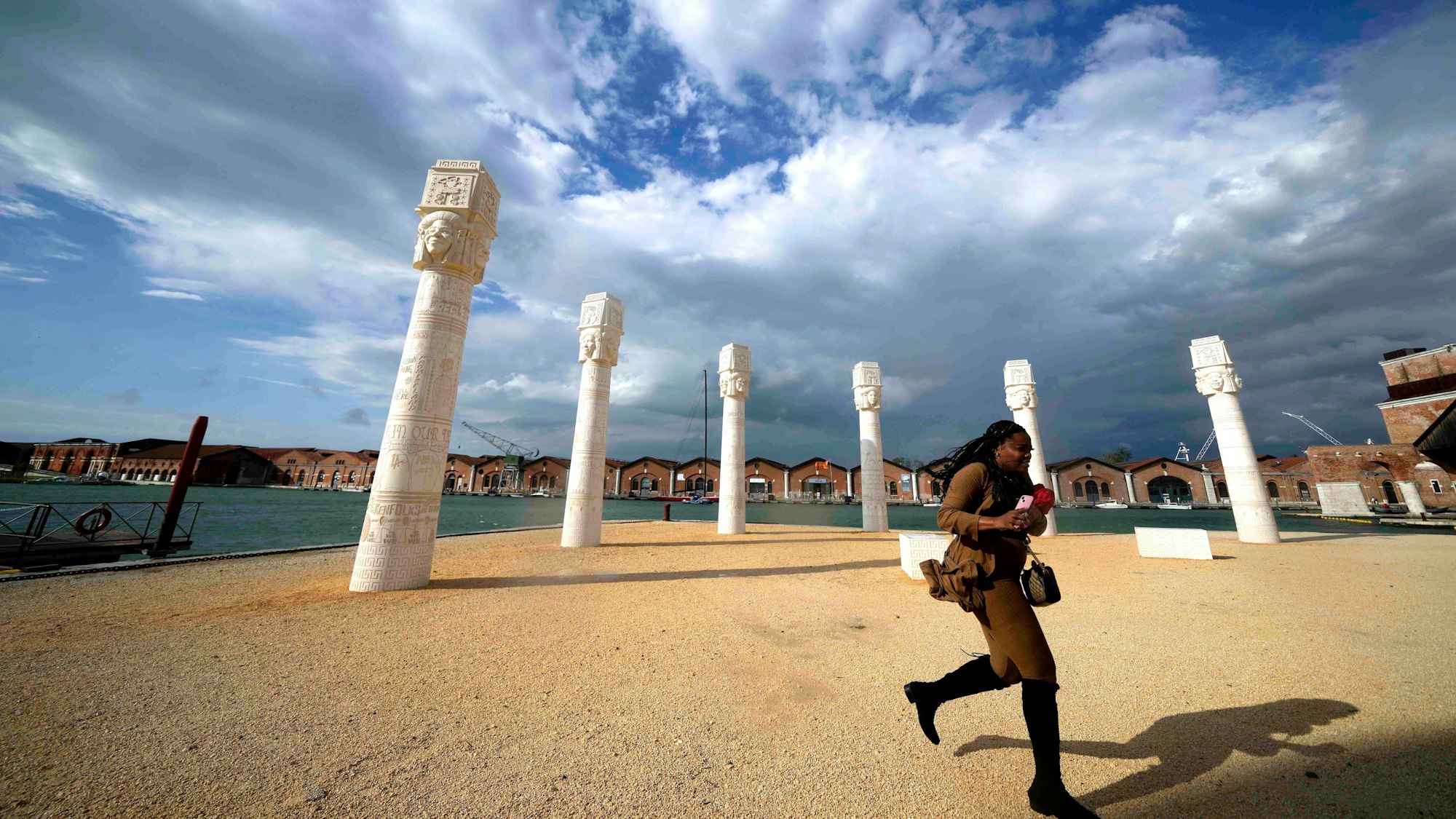 Ein Besucher läuft vor einer Reihe von Stelen vorbei, der Himmel ist bewölkt..