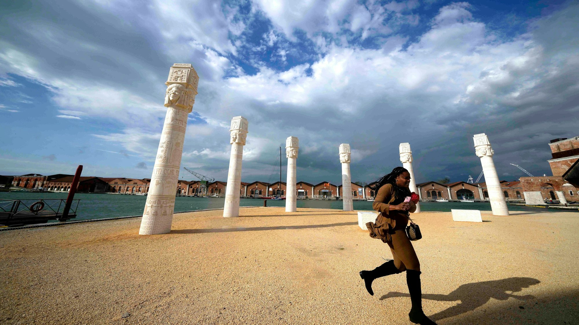 Ein Besucher läuft vor einer Reihe von Stelen vorbei, der Himmel ist bewölkt..